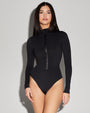 Model is posing in Surfy - Black One Piece Long Sleeve Shapewear Swimsuit full front view closed zipper 