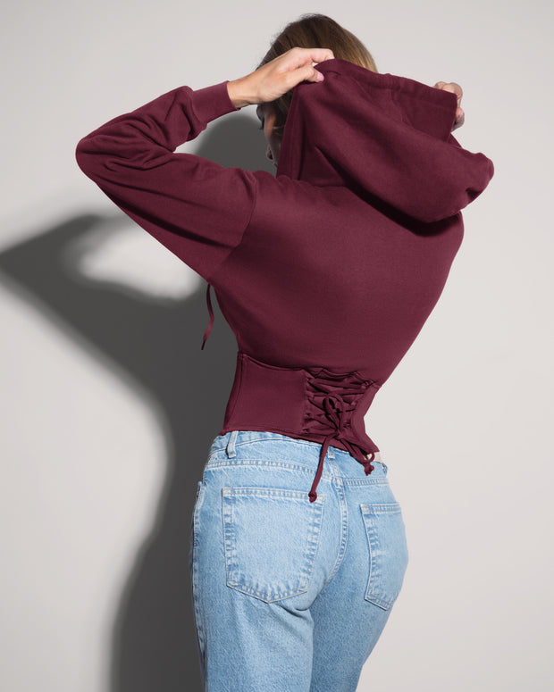 Model is wearing Corsety Long Sleeve Shapewear Hoodie - Dark Cherry back view